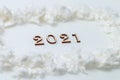 Little wooden year numbers on a white background with artificial snow