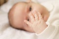 Little hands of newborn.Newborn baby in a white bodysuit lying on the bed. Top view of a newborn baby on a white warm Royalty Free Stock Photo