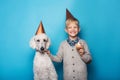 Little handsome boy with dog celebrate birthday. Friendship. Love. Cake with candle. Studio portrait over blue background Royalty Free Stock Photo