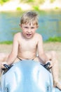 Little handsome boy on inflatable swimming toy sitting astride. Child on vacation on the pond