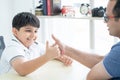 Little handsome Indian child son and his father, have fun playing, competing in finger or hand wrestling together on table at home