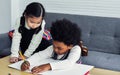 Little happy African black boy and caucasian sweet girl wearing casual sweaters, smiling, sitting together in living room at home Royalty Free Stock Photo