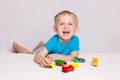 Little happy blond boy playing colored cars on white background