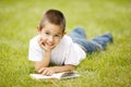 Little happy boy reads book lying on grass Royalty Free Stock Photo