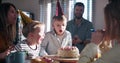 Little happy Caucasian boy child making wish, blow on birthday cake at surprise family party with confetti slow motion. Royalty Free Stock Photo