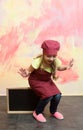 Little happy chef sitting on blank cook restaurant menu board