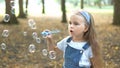 Little happy child girl blowing soap bubbles outdoors in summer park Royalty Free Stock Photo