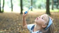 Little happy child girl blowing soap bubbles outdoors in summer park Royalty Free Stock Photo