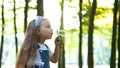 Little happy child girl blowing soap bubbles outside in green park. Outdoor summer activities concept Royalty Free Stock Photo