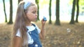 Little happy child girl blowing soap bubbles outside in green park. Outdoor summer activities concept Royalty Free Stock Photo