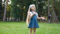 Little happy child girl cathing and bursting soap bubbles outdoors in summer Royalty Free Stock Photo