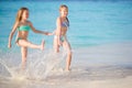 Two little happy girls have a lot of fun at tropical beach playing together at shallow water. Royalty Free Stock Photo