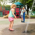 Little happy children playing at water splash pad fountain in park playground on hot summer day Royalty Free Stock Photo