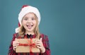 Little happy face girl in christmas hat holding present box. Kid in santa\'s hat with gift in hands empty copy space