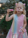 Little happy funny girl with blond hair blowing soap bubbles in amusement park Royalty Free Stock Photo