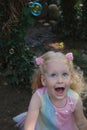 Little happy funny girl with blond hair catching soap bubbles in amusement park Royalty Free Stock Photo