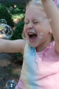 Little happy funny girl with blond hair catching soap bubbles in amusement park Royalty Free Stock Photo