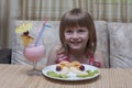 Little happy girl eating fruit salad and strawberry milkshake, closeup. Healthy food for children Royalty Free Stock Photo