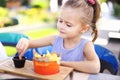 Little happy girl eating rench fries with sauce at street cafe outside. Royalty Free Stock Photo