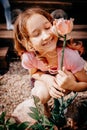 Little happy girl with a flower in her hands at the summer cottage in a pink t-shirt.