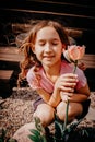 Little happy girl with a flower in her hands at the summer cottage in a pink t-shirt. Royalty Free Stock Photo