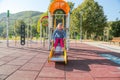 Little happy girl playing in children`s slide in colorful modern playground for kids.
