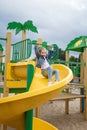 Little happy girl playing having fun on playground among colorful slides, carefree childhood concept.