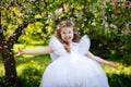 A little happy girl plays under a blooming apple tree. The child throws the petals of pink flowers. Summer fun for families with Royalty Free Stock Photo