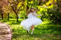 A little happy girl plays under a blooming apple tree. The child throws the petals of pink flowers. Summer fun for families with Royalty Free Stock Photo