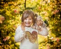 Little happy Girl with Plushy Animal waving and smiling on a sunny Fall Day