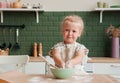 Little happy girl prepares dough in the kitchen. Child pastry chef in the kitchen
