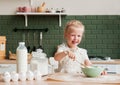 Little happy girl prepares dough in the kitchen. Child pastry chef in the kitchen