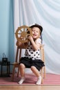 Little happy girl sits with steering wheel and plays sailor Royalty Free Stock Photo