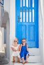 Little happy girls in dresses at street of typical greek traditional village on Mykonos Island, in Greece Royalty Free Stock Photo