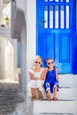 Little happy girls in dresses at street of typical greek traditional village with white walls and colorful doors on Royalty Free Stock Photo