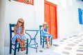 Little happy girls in dresses at street of typical greek traditional village on Mykonos Island, in Greece Royalty Free Stock Photo