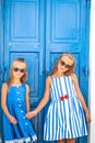 Little happy girls in dresses at street of typical greek traditional village on Mykonos Island, in Greece Royalty Free Stock Photo