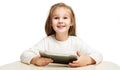 Little happy preschool girl sitting at the table holding a tablet in her hands and smiling with a wide smile on a white cut-out Royalty Free Stock Photo