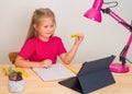 Little happy preschooler girl learning English online at home with tablet computer Royalty Free Stock Photo