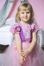 Little happy princess girl in pink dress and crown in her royal room posing and smiling. Royalty Free Stock Photo