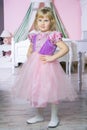 Little happy princess girl in pink dress and crown in her royal room posing and smiling. Royalty Free Stock Photo