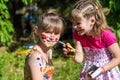 Little happy sisters play with colors in the park, children play, children paint each other Royalty Free Stock Photo