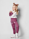 Little happy smiling girl posing in sportswear and sneakers on gray background. Royalty Free Stock Photo