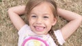 Little Happy toothless and Smiling Child Girl Laying on Yellow Lawn Dry Grass Hay in Park. Summer Time, Nature, Dreams Royalty Free Stock Photo