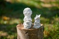 Little hedgehog statue near pile of books sits on wooden stump at green background