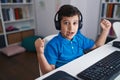 Little hispanic boy using computer laptop at the school screaming proud, celebrating victory and success very excited with raised Royalty Free Stock Photo