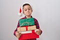 Little hispanic boy wearing christmas hat holding presents depressed and worry for distress, crying angry and afraid Royalty Free Stock Photo