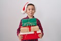Little hispanic boy wearing christmas hat holding presents puffing cheeks with funny face Royalty Free Stock Photo