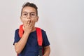 Little hispanic boy wearing glasses and student backpack covering mouth with hand, shocked and afraid for mistake Royalty Free Stock Photo
