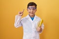 Little hispanic boy wearing scientist glasses smiling with an idea or question pointing finger with happy face, number one